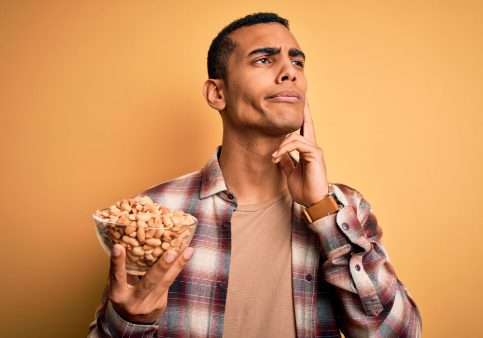Handsome,African,American,Man,Holding,Bowl,With,Heathy,Peanuts,Over