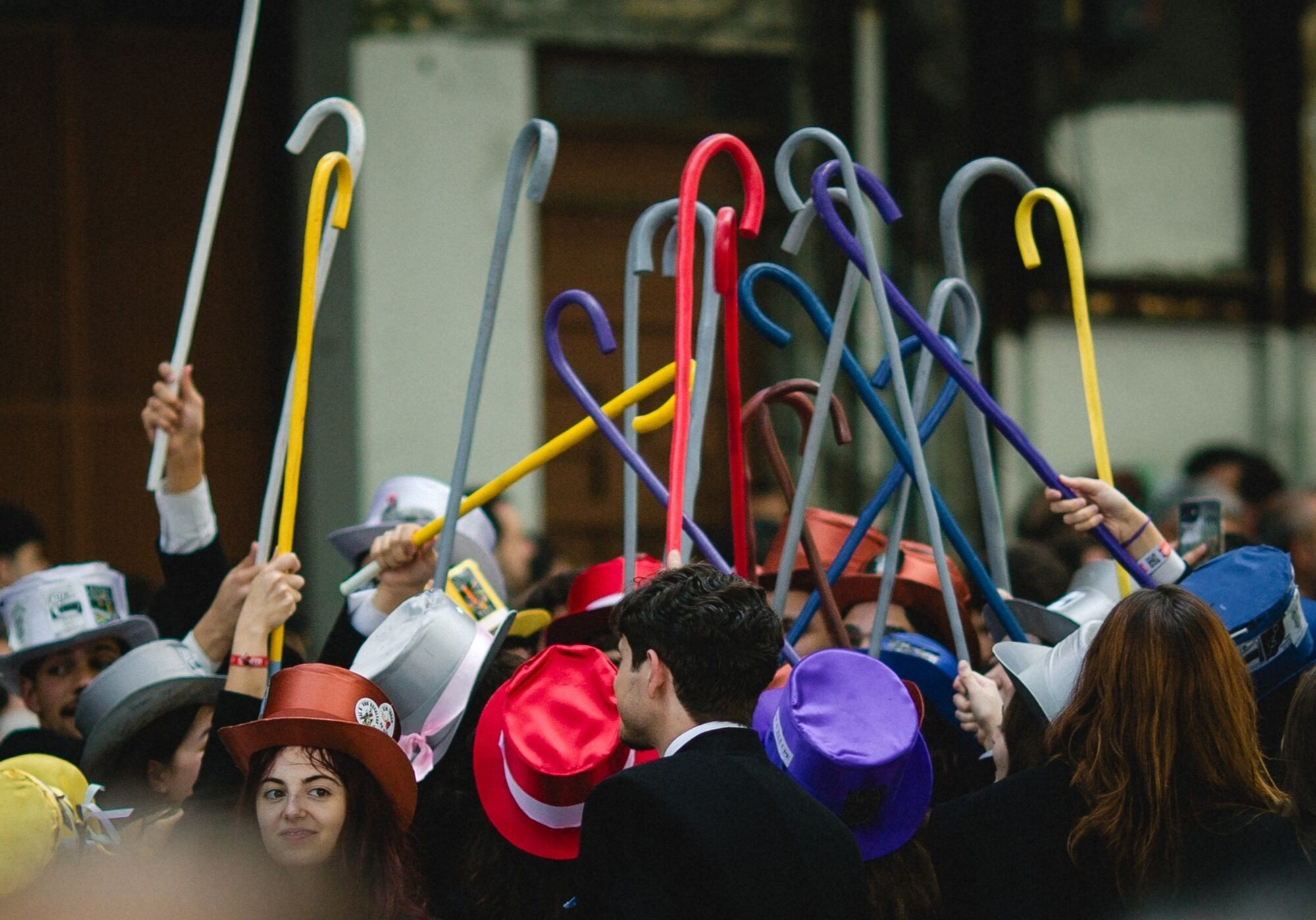 Group of students in colourful top hats holding up canes during the Queima das Fitas festival