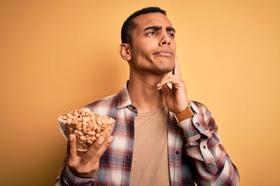 Handsome,African,American,Man,Holding,Bowl,With,Heathy,Peanuts,Over