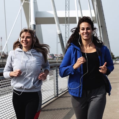 two women running with headphones on