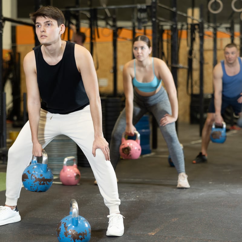 three people in the gym lifting kettlebells