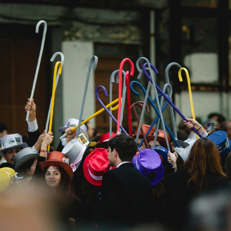 Group of students in colourful top hats holding up canes during the Queima das Fitas festival